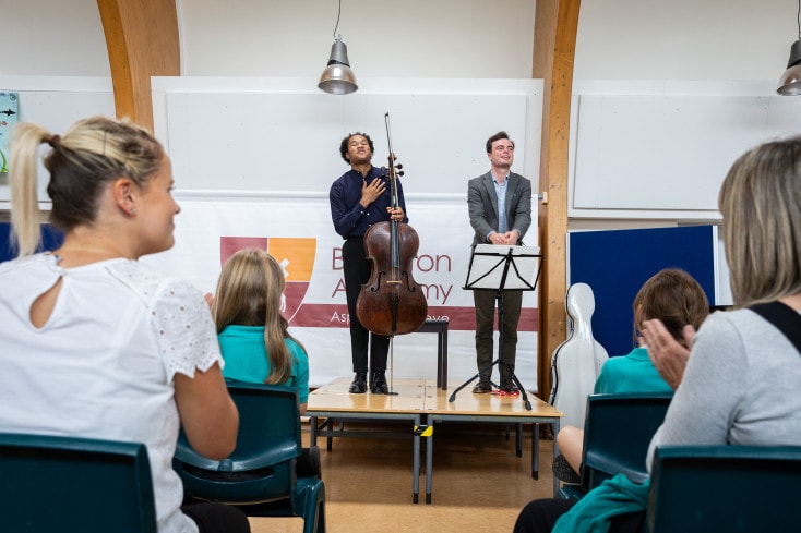 Sheku and BSO Assistant Conductor Tom Fetherstonhaugh on stage at Braunton Academy